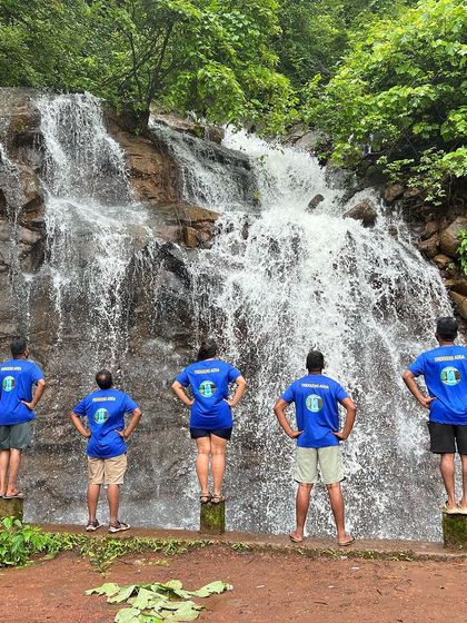 The team posing in their 'Trekkers Adda' t-shirts in front of a waterfall, showing our group pride.