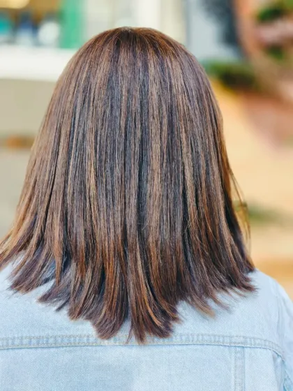 Straight, sleek, and shining with highlights. This look shows how expertly placed highlights can add incredible dimension and texture to a classic shoulder-length cut.