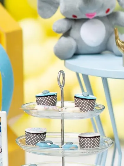 A close-up of the dessert table at the baby elephant party, featuring framed photos of the birthday boy and a hot air balloon prop.