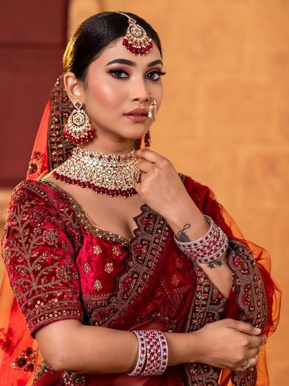 A portrait shot showing the intricate details of the red bridal lehenga and matching jewelry.