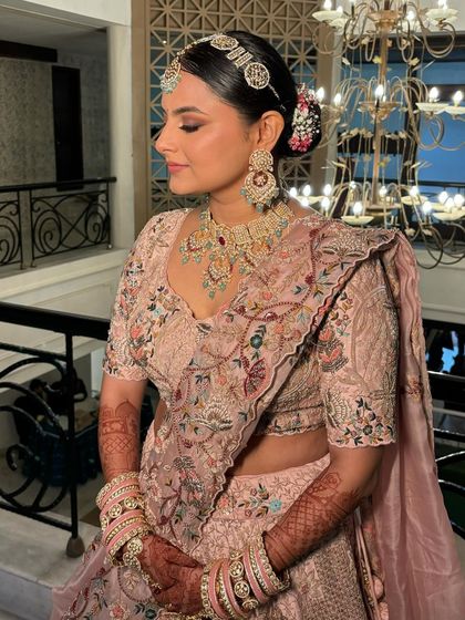 The side profile highlights the elegant hair bun and the soft contouring of her makeup.