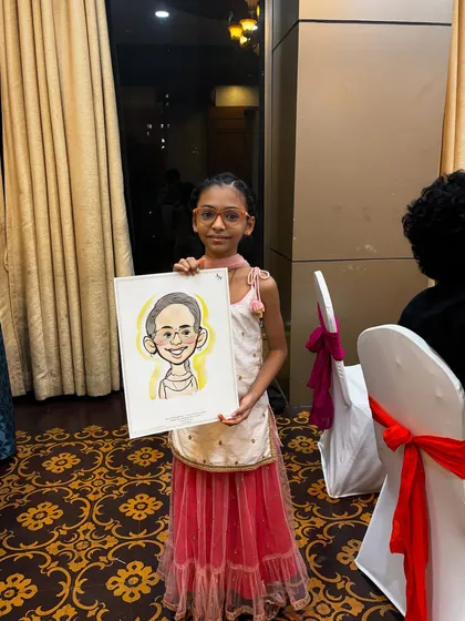 A young girl in a lovely pink outfit with her watercolor portrait. These live drawings make for wonderful memories of a special day.