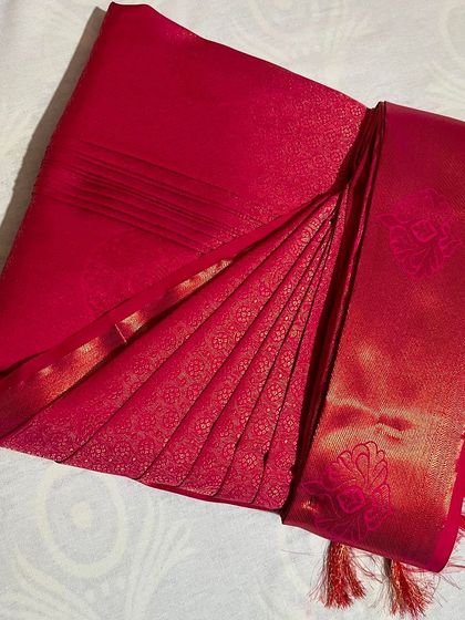 A close-up of a bright red silk saree with its pleats perfectly set. Notice the crisp folds and the neat fall, ready to create an elegant look instantly.