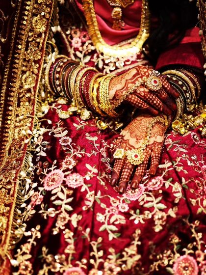 A close-up of the bride's hands, showing the incredible detail of her jewelry and the rich color of her henna stain.