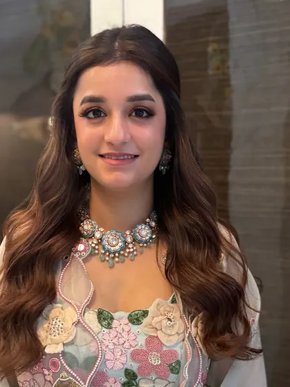 A beautiful client with a simple and elegant half-up style. The hair is softly waved and pinned back, letting her stunning floral outfit and necklace be the focus.