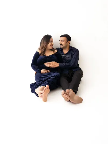 A fun and relaxed pose with the couple sitting on the floor together, sharing a happy and intimate moment.