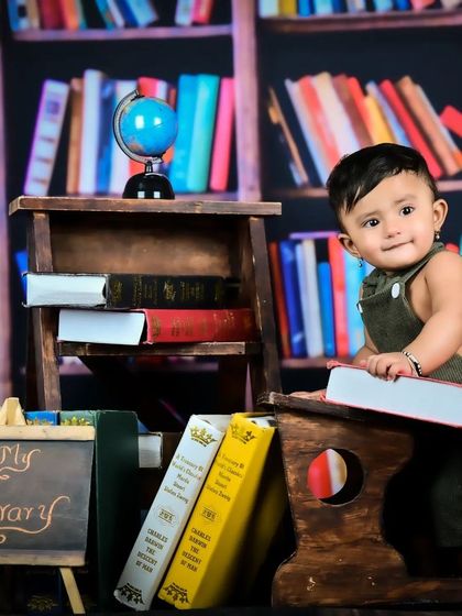 Another shot from the library theme, with the baby holding a large book and looking at the camera.