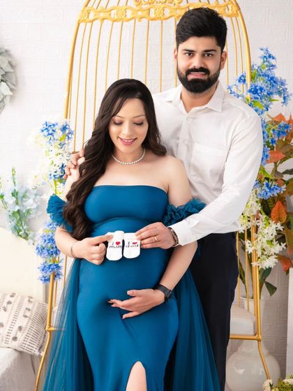 A sweet portrait of the couple holding "I love Mom" and "I love Dad" baby shoes. It's a creative way to express their excitement and love for their growing family.
