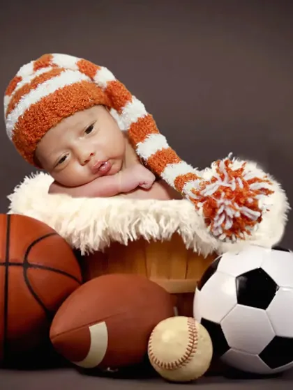 A sporty theme for a future athlete, with a baby surrounded by a basketball, soccer ball, and football.