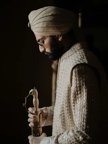 A moody and cinematic portrait of the groom, his focus on the traditional kirpan symbolizing strength and responsibility.
