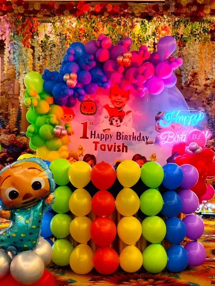A detailed shot of the Cocomelon birthday stage, featuring a neon "Happy Birthday" sign and a large number '1' light, making the decoration shine.