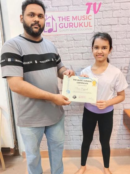 A student receives her certificate from our guitar coach. We make it a point to celebrate every milestone, whether it's completing a course or passing an exam.