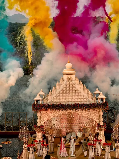 A magnificent temple-style mandap becomes the canvas for a vibrant celebration. The explosion of colored smoke marks a joyous union, blending tradition with a modern, festive spirit.