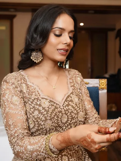 A close-up of the bride examining her henna. The matte makeup provides a beautiful, non-reflective finish that is perfect for photography.