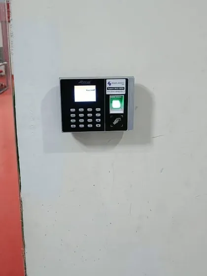 A clean installation of a biometric attendance machine on a plain wall. This setup is perfect for corporate offices looking to track employee time and secure entry points.