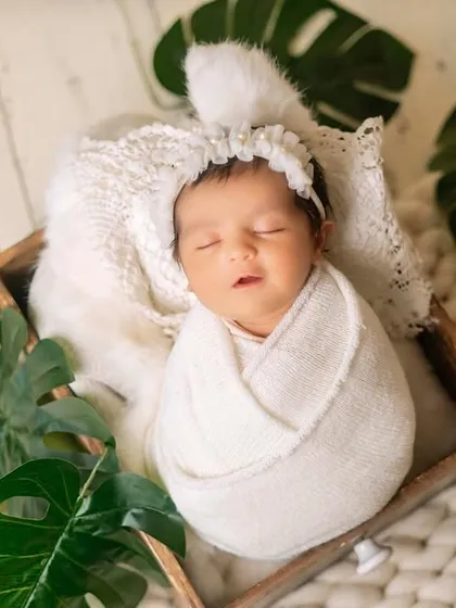 Another angle of the baby wrapped in white, nestled in a wooden box. The overhead shot emphasizes how tiny and peaceful they are in their first few days.