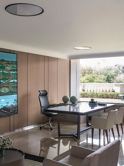 This director's cabin in 'The Layered Office' features a large desk and expansive windows with views of the surrounding area. The design is clean and modern, with a focus on creating a spacious and light-filled executive office.
