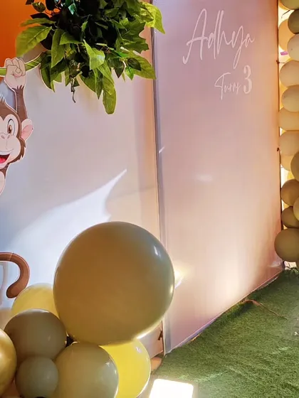 A detailed shot of a monkey-themed party, showing a cute monkey cutout swinging from a vine against an orange wall.