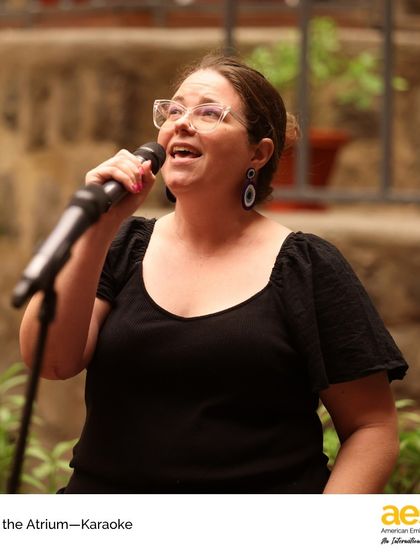 A teacher sings her heart out during 'Arts in the Atrium: Karaoke'. Our faculty often joins in the fun, modeling a love for the arts and building a joyful, supportive community atmosphere.