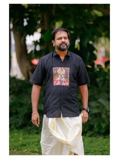 A classic portrait of the model, showcasing the unique graphic on the shirt and the traditional Onam attire.