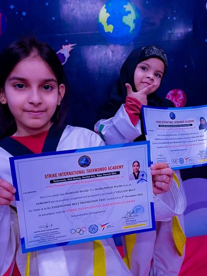 Two of my students proudly show off their official certificates after successfully passing their yellow belt promotion test.