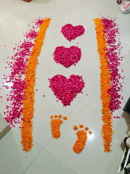 A beautiful flower petal rangoli I created for a baby girl's welcome. The design features hearts and tiny footprints made from pink rose and orange marigold petals.