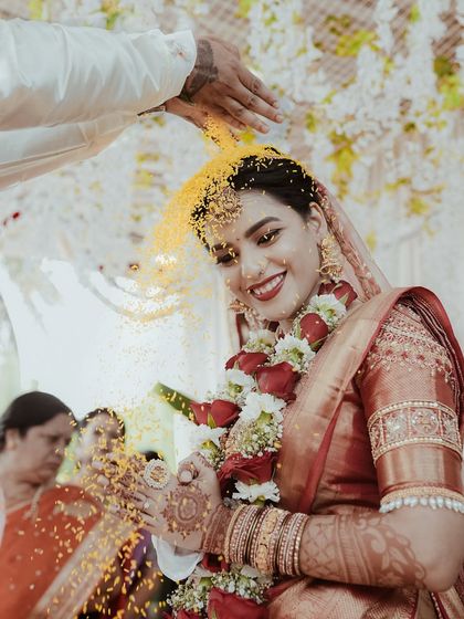 The bride beams with happiness as she is showered with yellow rice, a traditional blessing. This candid shot captures the color and emotion of the moment perfectly.