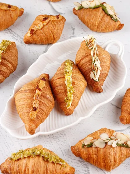 A beautiful flat lay of assorted sweet and savoury croissants, emphasizing their flaky layers and fresh toppings.
