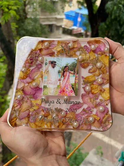 A lovely 6x6 inch square keepsake held up against a natural background. The combination of pink and yellow rose petals with pearls gives it a soft, romantic feel.