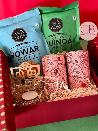 Light up your employees' Diwali with our special corporate hampers. This festive red box includes healthy snacks like Jowar and Quinoa puffs, along with decorative tins and a Ganesha T-light holder.