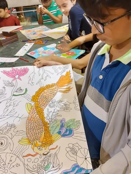 A student proudly shows his work-in-progress on the lucky carp. The detail in the scales is a testament to his focus and patience.