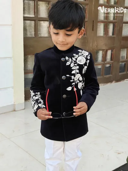 A full-length shot of our client looking dapper in the black velvet Indo-western jacket. Paired with white pants, it creates a striking, high-contrast look perfect for a wedding baraat.