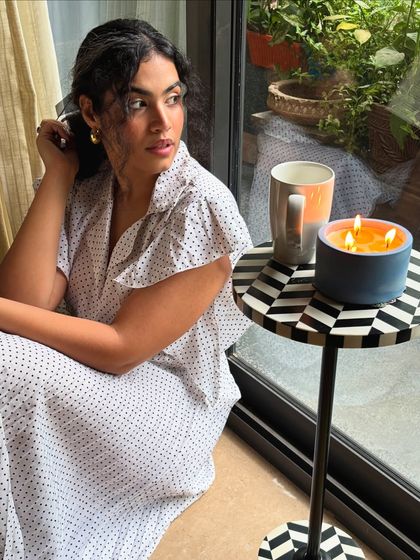 Naval Ravikant is the only man I'm into right now. A quiet, rainy day moment with a book, a coffee, and a Sabhi candle, creating a peaceful, aesthetic vibe.