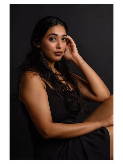 A simple and elegant portrait against a dark background. The focus is on the model's natural beauty and serene expression.