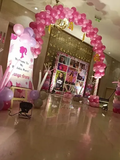 A glamorous entrance setup for a birthday party, featuring a pink balloon arch and a personalized welcome sign with a photo collage.