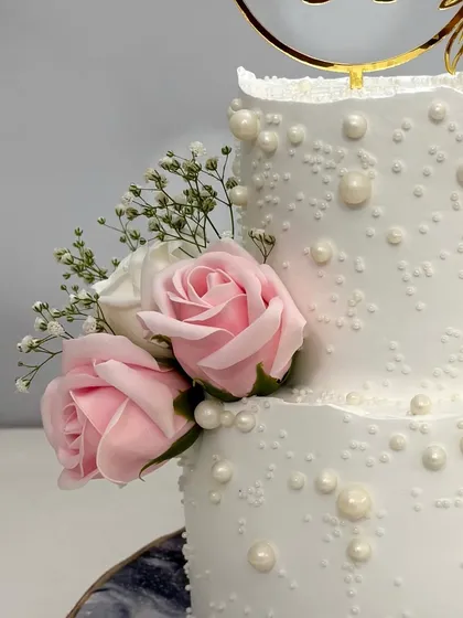 A close-up of the delicate pink roses and edible pearls on this two-tier engagement cake. It’s these small, handcrafted details that make each cake truly special.