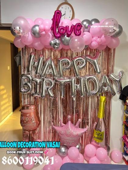 A fun and girly birthday setup with a pink shimmer curtain. The decor includes "Happy Birthday" foil balloons and other party props.