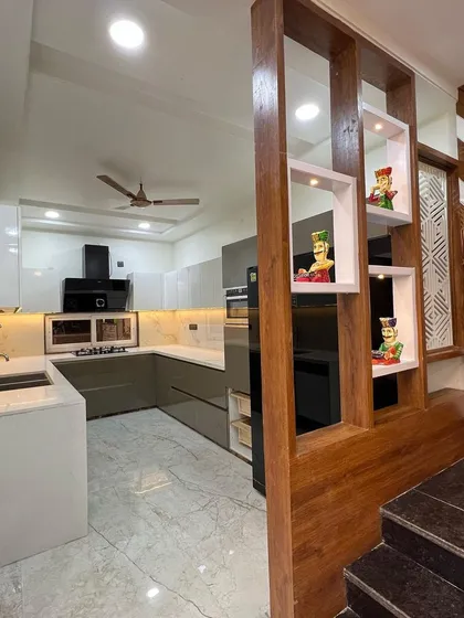 From this angle, you can see the wooden partition with built-in display niches that separates the kitchen from the staircase, adding a decorative touch while maintaining an open feel.