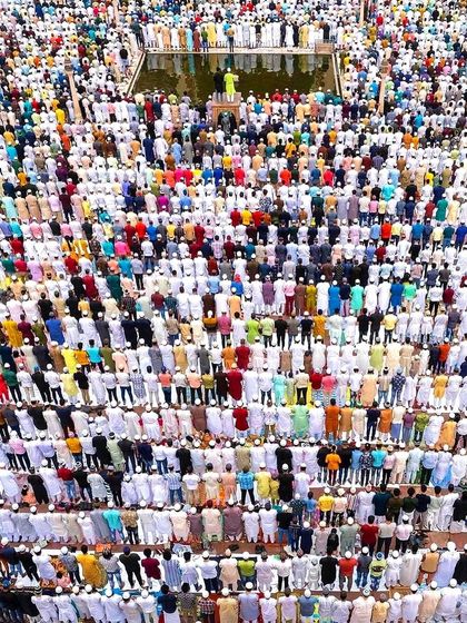 This striking top-down photograph captures the organized rows of worshippers during Eid prayers. The vibrant colors of their attire stand out against the white prayer mats, creating a visually stunning pattern of unity and devotion.