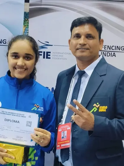 A coach and student celebrate a hard earned diploma at the FIE Women's Satellite Tournament. This moment captures the proud mentorship that guides our athletes to success on the international stage.