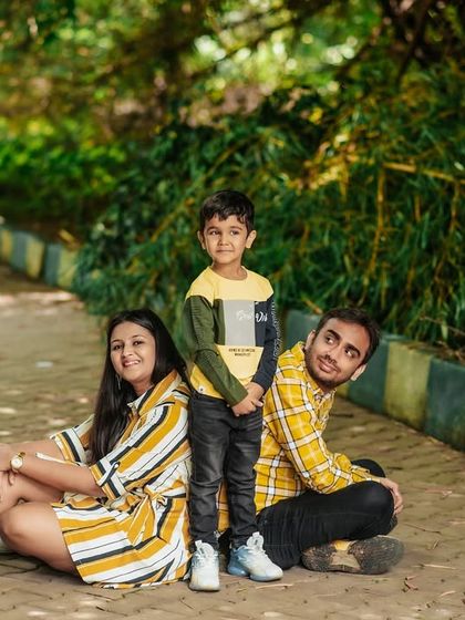 A relaxed family portrait in the park. The coordinated yellow outfits and casual poses reflect their fun and easygoing dynamic.