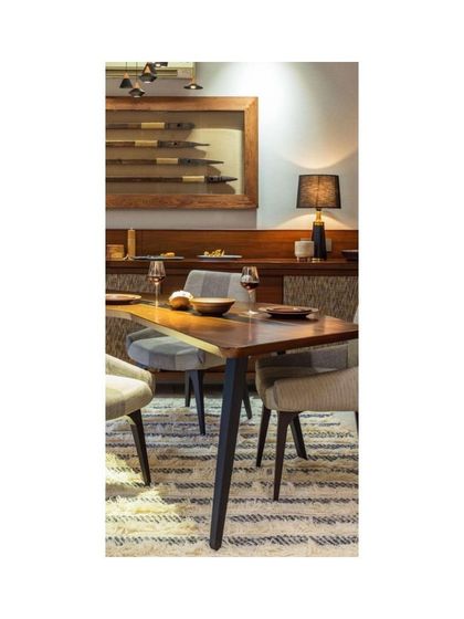 A close-up of the dining setting at Treetops. The unique shape of the table encourages conversation, while the warm wood tones and soft upholstery of the chairs create an inviting atmosphere for shared meals.