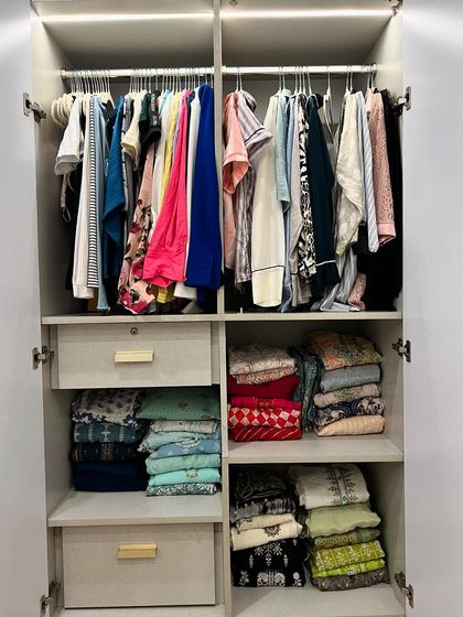 This wardrobe uses a combination of hanging space for daily wear and deep drawers with neatly stacked ethnic wear, showing a practical way to organize different clothing types.