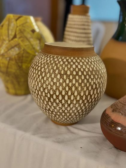 This is one of my favorite surface decoration techniques. I apply a layer of white slip over the pot and then carve through it to create these intricate, dotted patterns.