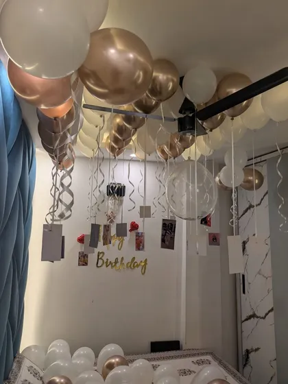 A detailed shot of the ceiling balloons with hanging photos and curly ribbons, a popular choice for romantic birthday surprises.