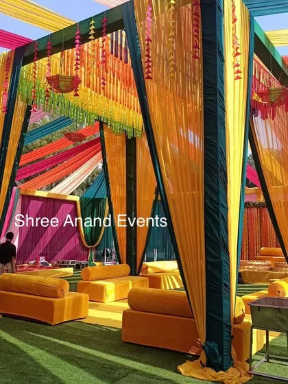 A beautiful Haldi or Mehndi seating area, with vibrant yellow and green drapes and comfortable floor seating.