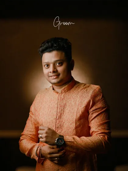 A handsome portrait of the groom, adjusting his watch and smiling, ready to celebrate his wedding reception.
