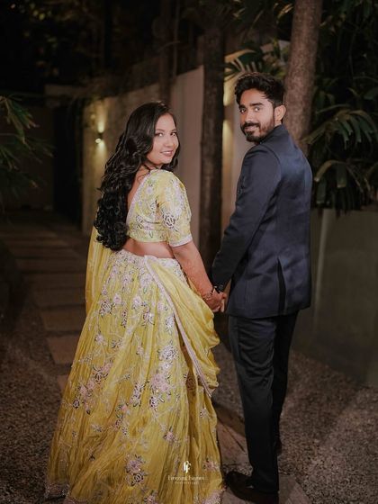 A "follow me" style shot of the couple walking hand-in-hand at their evening engagement event, capturing the magic of the night.