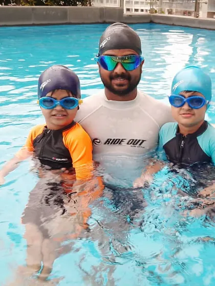 I believe in a hands-on approach, which is why I am always in the pool with my students. This photo is from a private lesson at a client's residential pool, where I am coaching two young siblings together.