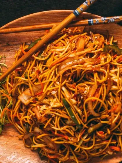A plate of our delicious Hakka noodles. It's a classic comfort dish, perfectly cooked and tossed with fresh vegetables, served on a wooden platter.